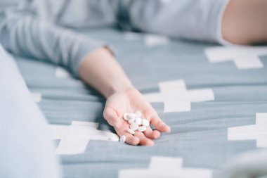 woman lying in bed with pills in hand It's a way to kill yourself with an overdose.