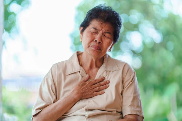 Elderly women with chest pain and wheezing Caused by shock or regret. Concept of health problems in the elderly.