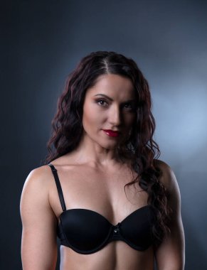 Stüdyoda poz veren siyah saçlı, bronzlaşmış vücutlu güçlü vücut geliştirici kadın portresi.