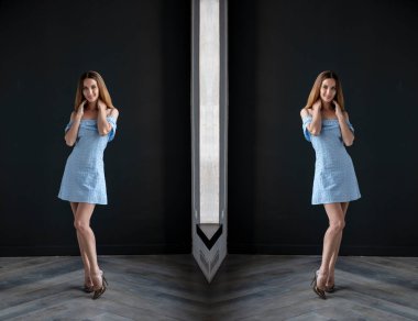 mirrored shot of slim blonde young woman wearing top and shorts posing on dark background