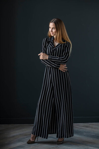 portrait of beautiful young woman in black dress on dark background