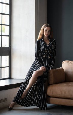 beautiful woman posing in studio wearing striped dress 