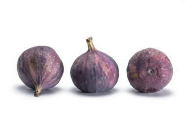 Beyaz zemin üzerinde farklı taraflardan üç olgun incir yakın