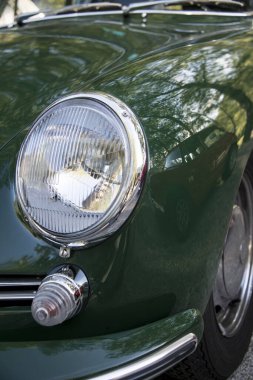 Klasik yeşil bir spor arabanın ön ve arka farlarının kısmi görüntüsü