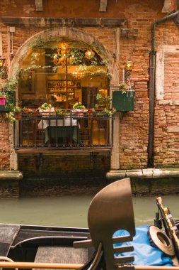 Venedik 'te bir kanalda romantik bir restoran. Ön planda bir gondol var.