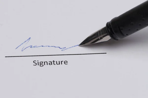 在白纸上关闭钢笔 并在签名线上签名 免版税图库图片