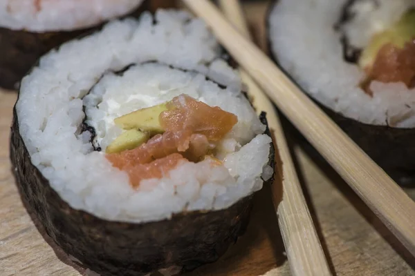 Zbliżenie Jednej Rolki Sushi Drewnianej Płycie Ogórkiem Ryżowym Łososiem Obok — Zdjęcie stockowe