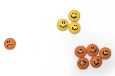 Mutluluğu temsil eden yüzleri olan iki yuvarlak şeker grubu ve beyaz arka planda tek başına kalmış üzgün bir adam.