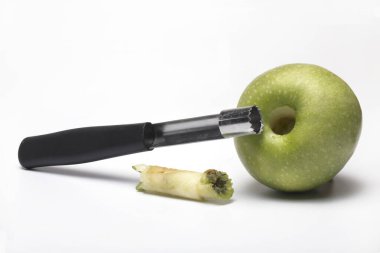 Close up of apple case corer for coring with a cored Granny Smith apple and the coring case next to it isolated on white background clipart