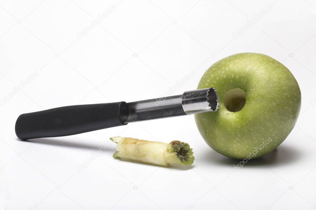 Close up of apple case corer for coring with a cored Granny Smith apple and the coring case next to it isolated on white background