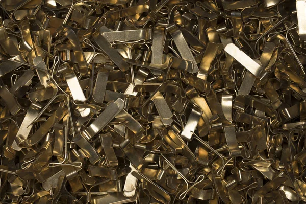 Close up of pile of several brass metal gold staples for sealing cushion envelopes one on top of the other also for use as a background