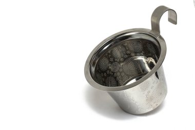 Beyaz arka planda çay süzgeci olarak fincana asılabilecek metal gümüş kazanı kapat
