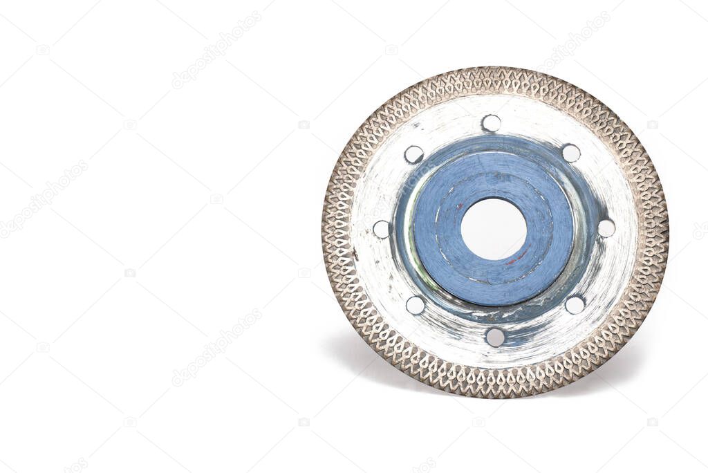 Close up of heavily used shiny silver metal and blue special carbide cutting disc for cutting tiles and stone slabs for use in angle grinder when laying tiles on white background