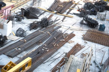 İnşa alanı, çeşitli çaplarda işlenmek üzere hazırlanmış düz yapısal çelik çubuklarla dolu..