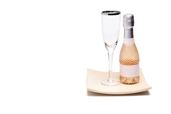 白を基調とした曲線を描く松の木の板の上に銀の縁を持つ高貴なガラスの横にシャンパンの小さなボトルのクローズアップ単一のお祝いのための概念として — ストック写真
