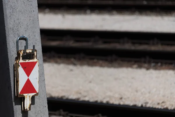 靠近几个铁轨末端信号标志板 其红色的白色三角形悬挂在铁轨旁边的连锁推车杆上 — 图库照片