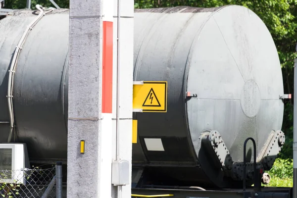 Üstten elektrik hattı tamir etmek için beton bir direk açık sarı elektrik tehlike işareti ve arka planda sıvı yanıcı maddeler için bir tank vagonu.