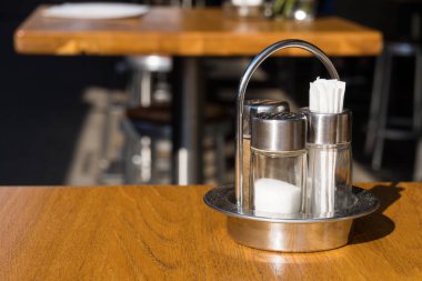 Açık hava yuvarlak bar masasını kürdanlarla, tuz ve biberliklerle kaplayın gümüş metal stantlar gibi.