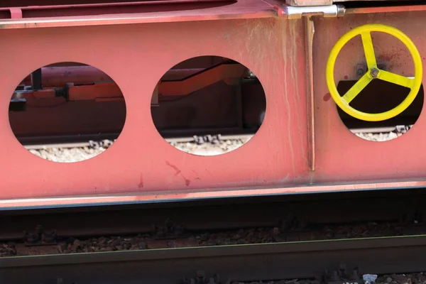 带有明显黄色转轮的实心钢制铁路低载重车厢侧视图及停放在轨道上的制动器锁定装置 — 图库照片
