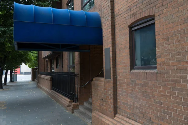 Brick tenement apartment building or hotel with representative entrance with blue round canopy as business entrance and welcome concept