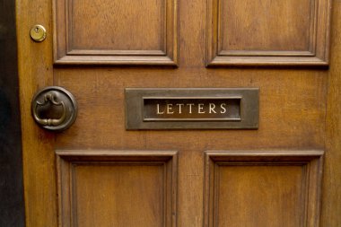 Close up of brown high quality noble wood entrance door with brass copper metal mail slot and inscription Letters as a concept for letter delivery and mailings