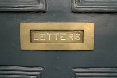 Painted solid dark green entrance door metal brass gold letter slot ornament inscription letters as a concept for postage mailings and old doors