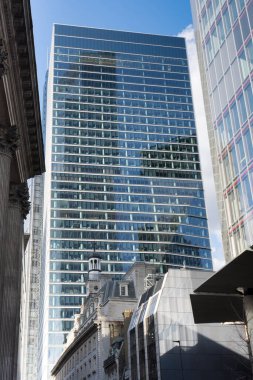 Londra 'daki şehir manzarası, tarihi alçak binaların arkasındaki yüksek gökdelen, mavi gökyüzüne karşı eski ve modern mimarinin konsepti.