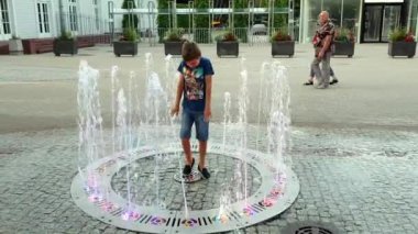 Çocuk, renkli fıskiyede oynarken iyi eğlenceler.