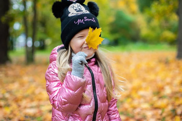 Ein Mädchen hält ein großes gelbes Ahornblatt in der Hand. — Stockfoto