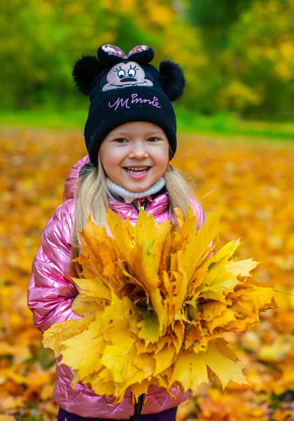 Ein Mädchen hält einen großen Strauß Ahornblätter in der Hand — Stockfoto