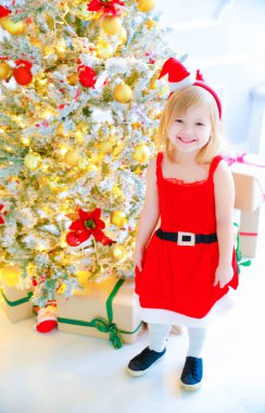 Noel Baba şapkalı kız yılbaşı süslemelerinde duruyor.