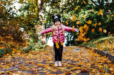 Bir kız bir sürü sarı akçaağaç yaprağı kusar.