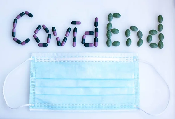 Felirat Covid End színes tabletta orvosi maszkkal — Stock Fotó