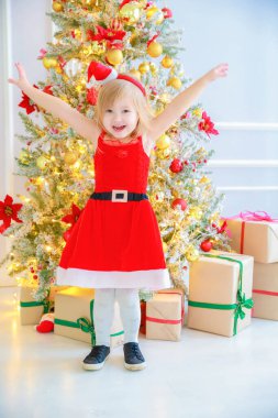 Noel Baba şapkalı kız yılbaşı süslemelerinde duruyor.