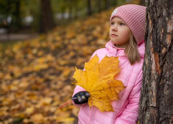 一个女孩手里拿着一片黄色的枫叶. — 图库照片