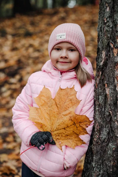 Bir kız elinde büyük sarı bir akçaağaç yaprağı tutuyor.. — Stok fotoğraf