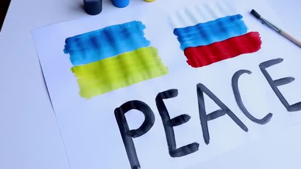 Plakát Ukrajna és Oroszország zászlajával és az angol béke feliratával, fehér asztalon fekszik.Lassú mozgás