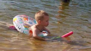 Çocuk gölde şişme yüzük ve su tabancasıyla yüzüyor, Marupe, Letonya - 07 Temmuz 2021