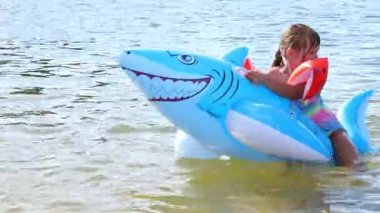  Gölde köpek balığı oyuncağında yüzen mutlu kız, Marupe, Letonya - 07 Temmuz 2021