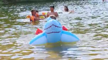  Gölde köpek balığı oyuncağında yüzen mutlu kız, Marupe, Letonya - 07 Temmuz 2021