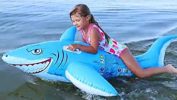 Boldog lány úszik egy felfújható cápajátékon a tengerben — Stock videók