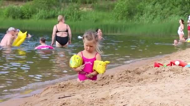 Glad flicka leker med sand i sjön solig sommardag, Marupe, Lettland - 07 juli 2021 — Stockvideo