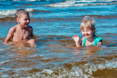 Avrupa görünümlü kız ve oğlan sahilde eğleniyor ve su sıçratıyor.