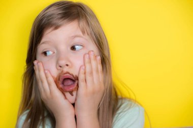 Frightened little girl eating chocolate dirty face