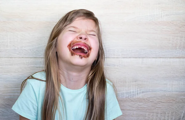 Laughing little girl eating chocolate dirty face — Stockfoto