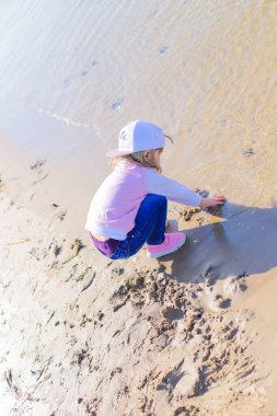 Mutlu çocuk kumsalda oynuyor.