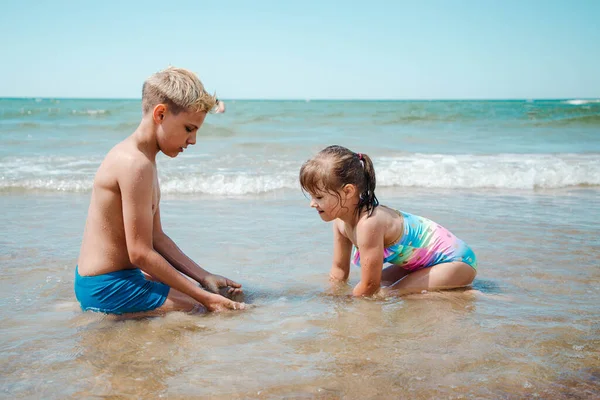 형제자매가 여름날 해변에서 물에서 재미있게 노는 모습 — 스톡 사진