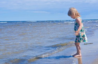 Yazın güneşli bir günde sahilde tek başına yürüyen kız çocuğu.