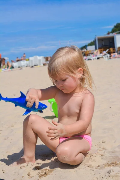 Щаслива дитина грає на пляжі з іграшковою акулою Ліцензійні Стокові Зображення