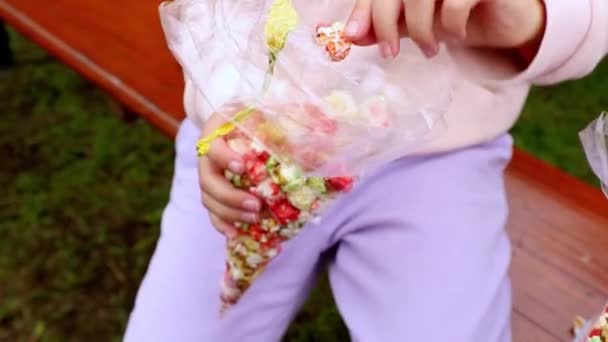Κορίτσι τρώει χρωματιστό ποπ κορν σε μια διαφανή τσάντα — Αρχείο Βίντεο